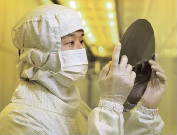 Worker Inspecting Silicon Wafer